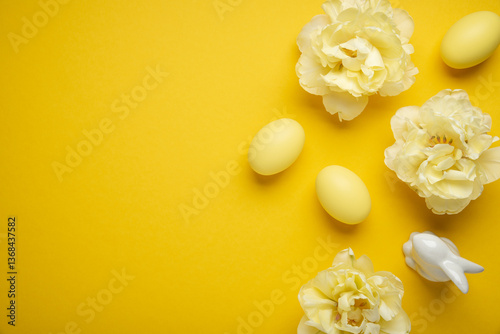Happy Easter holiday background. Easter eggs and tulip flowers on yellow background top view.