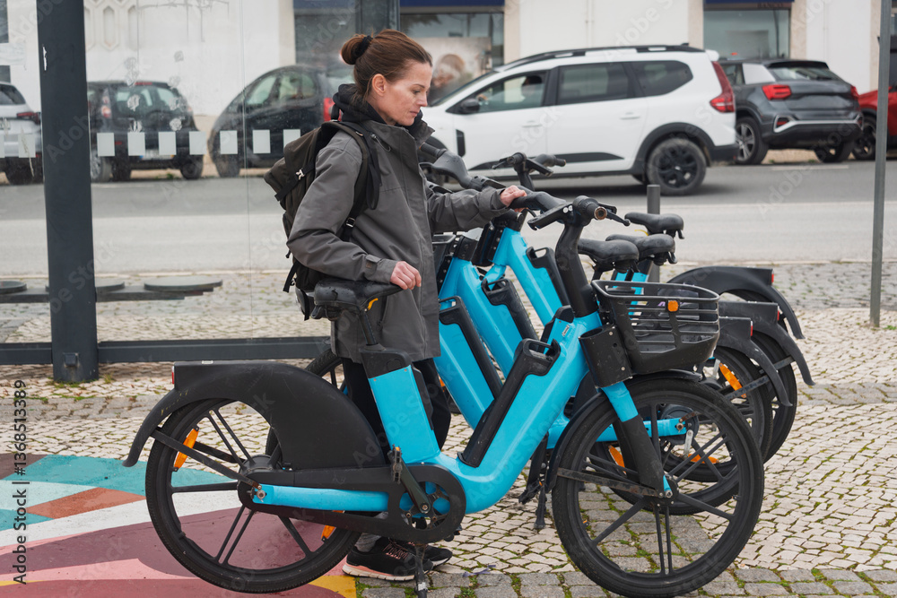 Fototapeta premium Woman holding a rental bicycle in a city street