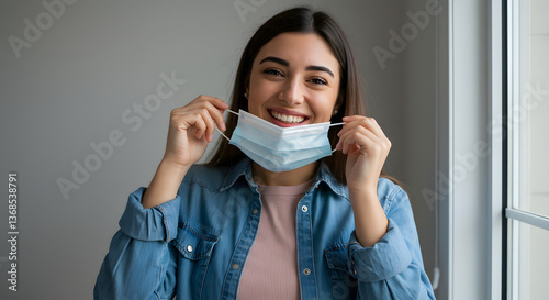 Wallpaper Mural Smiling Young Woman Removing Face Mask Indoors with Hopeful Expression Torontodigital.ca