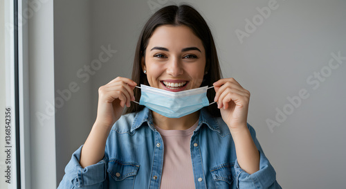 Wallpaper Mural Smiling Young Woman Removing Face Mask Indoors with Hopeful Expression Torontodigital.ca