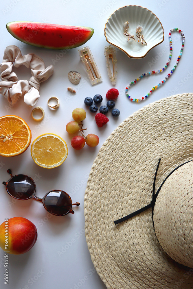 Straw hat, sunglasses, seasonal fruit, seashells and colorful accessories on white backgrounds. Cute summer essentials. Flat lay.