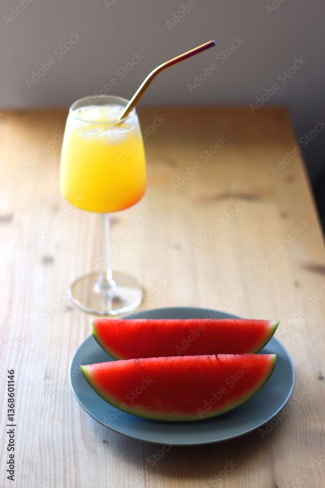Plate with two watermelon slices and glass of orange juice on the table. Selective focus.