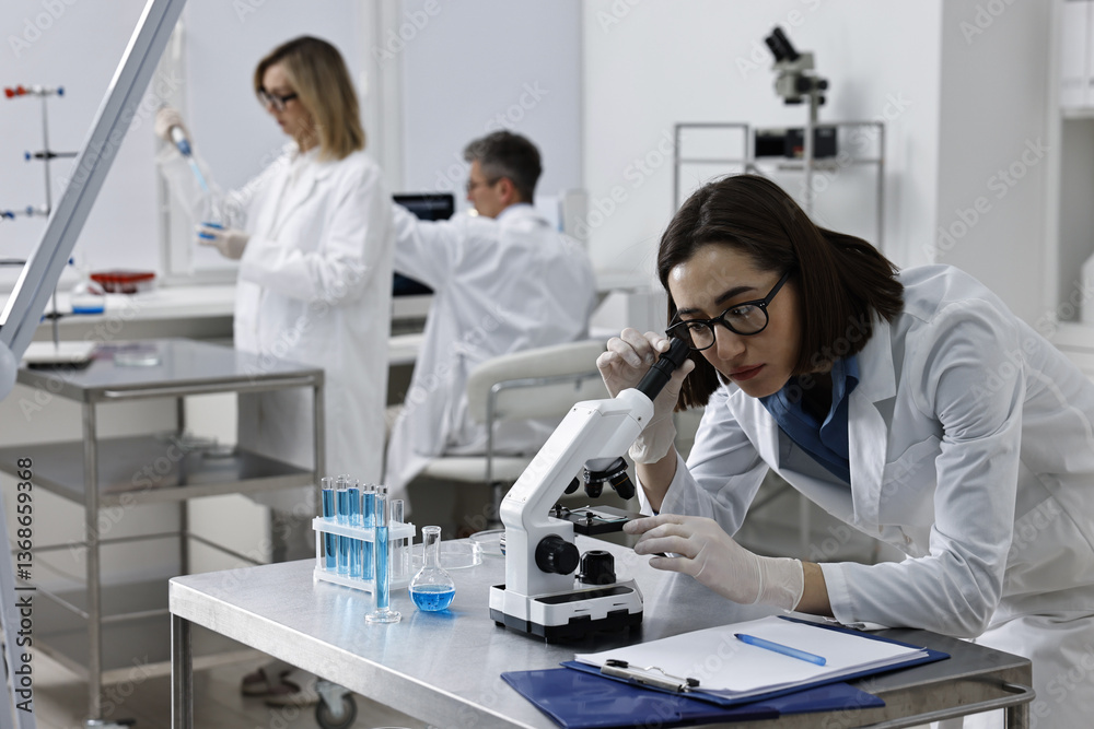 Scientist working with microscope at table in laboratory Scientist working with microscope at table in laboratory