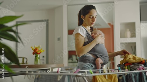 Cinematic shot of a mother carrying her newborn son while doing housework and dancing. Concept: woman power, happiness, family