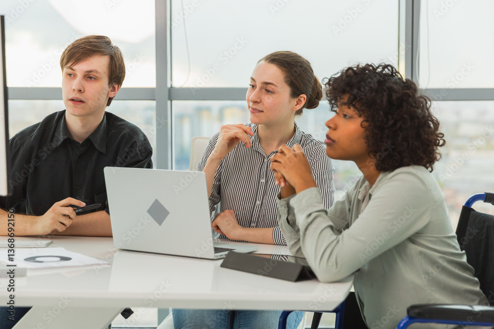 Teamwork brainstorm. Diverse multiracial colleagues woman in chair for people with disability working together. Group of people sitting in creative office discussing business. Young professional team Teamwork brainstorm. Diverse multiracial colleagues woman in chair for people with disability working together. Group of people sitting in creative office discussing business. Young professional team
