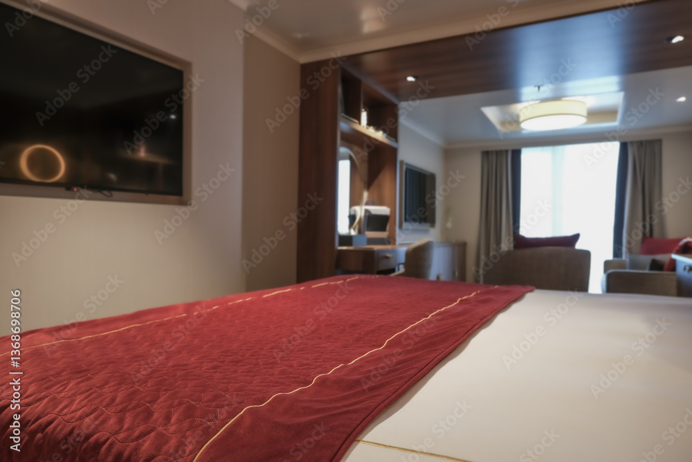 Luxurious mini suite stateroom cabin room onboard luxury cruise ship cruiseship ocean liner with bedroom and living area in red and creme with wood in modern Art Deco interior design
