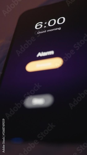 Vertical video. Close-Up View of Smartphone Alarm at 6 AM Propped on Pillow in Low Light with Soft Warm Background, Extreme Close-Up Low Angle, Early Comfort Concept