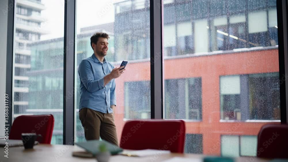 Office worker receiving salary notification on smartphone standing by window. Office worker receiving salary notification on smartphone standing by window.