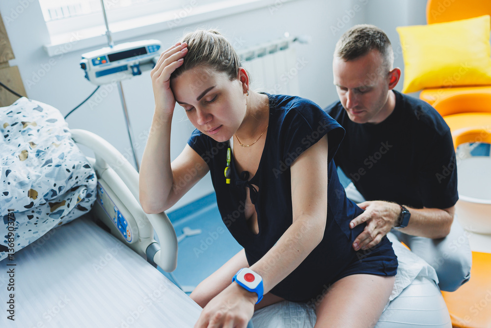 Pregnant woman feels severe pain during childbirth in hospital ward. Caring man helps woman during childbirth and massages her back. Support and love concept.