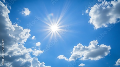 A radiant sun cutting through fluffy clouds in a clear blue sky. 