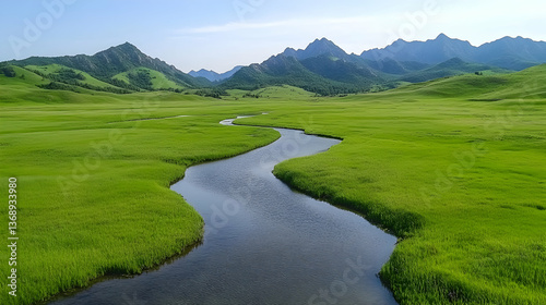 Serpentine river meandering through vibrant green valley, nestled against majestic mountain range under a clear sky