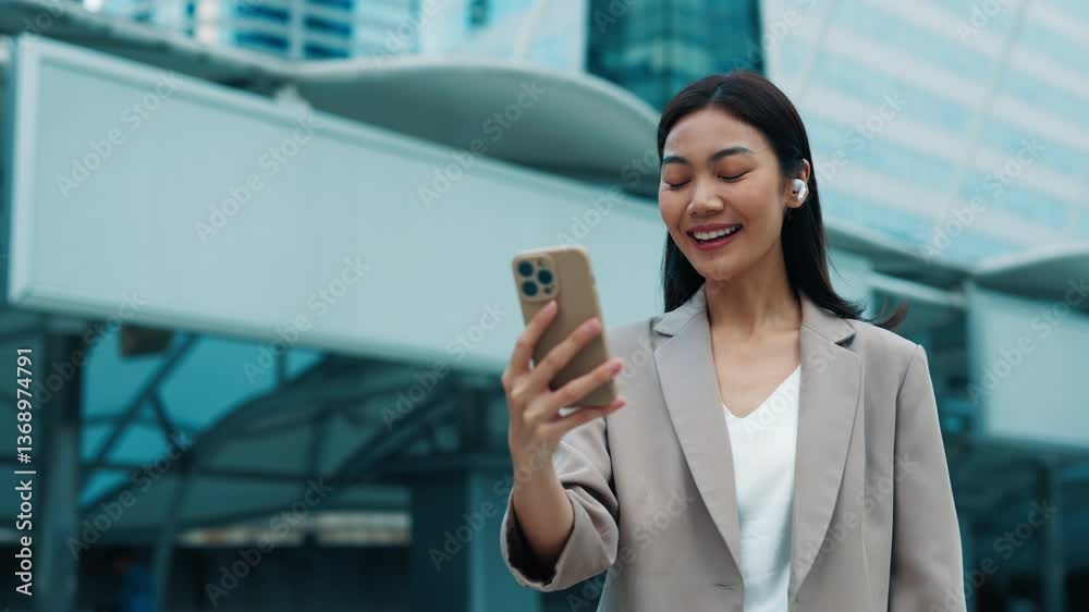 Portrait of Asian woman talking to partners on video chat standing near office building.