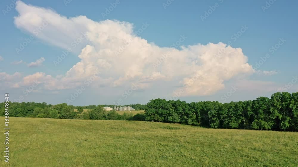 Aerial of a green pasture with a barn and silos in the background Aerial of a green pasture with a barn and silos in the background
