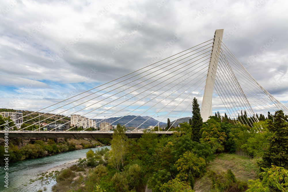 Fototapeta premium Panoramic view of Podgorica with Moraca river and modern Millennium bridge architecture in Montenegro's capital city