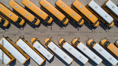 A row of yellow school buses are parked in a lot