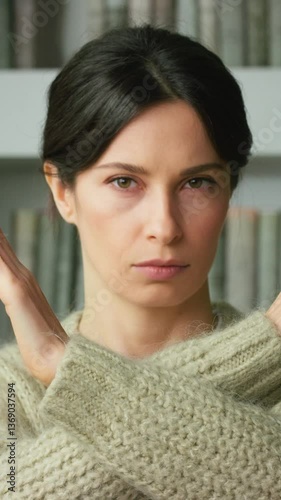 Portrait of young brunette woman showing forbidden sign, crossing her arms, making refusal gesture, negative, shaking her head, dissatisfied, serious girl says no. Gender violence and abuse concept