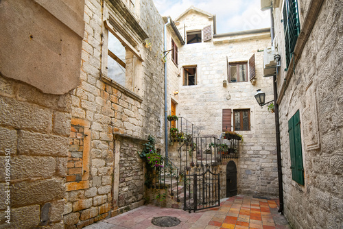 A picturesque corner with stairs leading from a gated entrance to an apartment in a residential district of the medieval old town of Kotor, Montenegro.