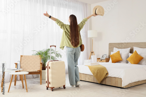 Happy female tourist with suitcase in hotel room