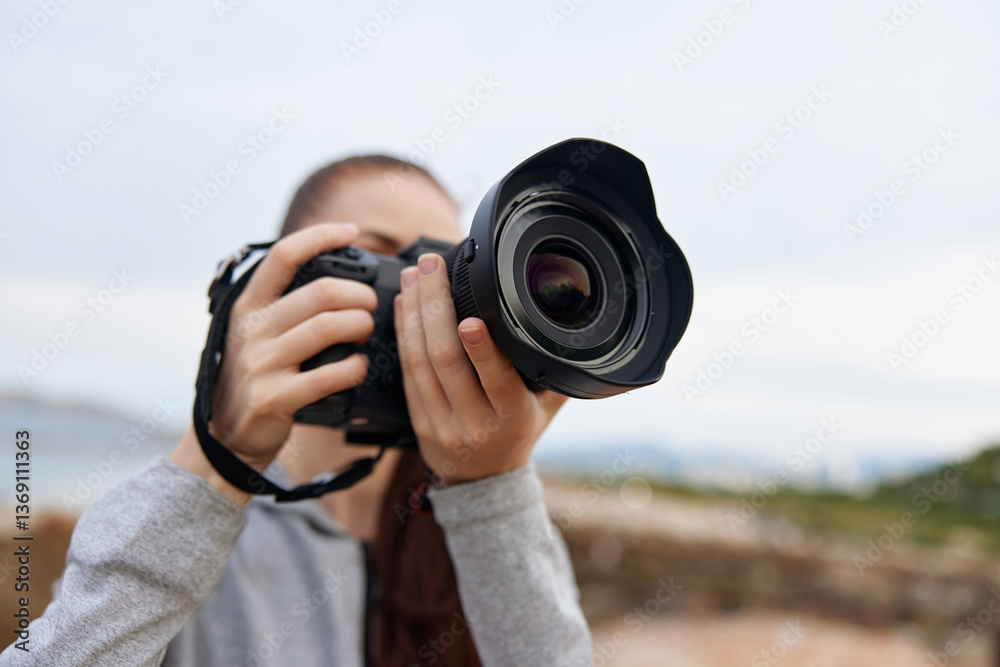 Obraz premium Young woman photography enthusiast capturing the beauty of nature with a digital camera, showcasing a passion for outdoor photography in a serene environment