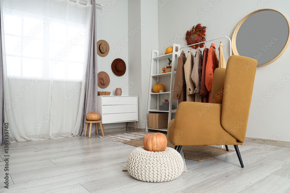 Fototapeta premium Interior of dressing room with coat rack, armchair and pumpkins