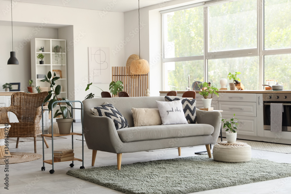 Interior of modern kitchen with sofa, counters and plants