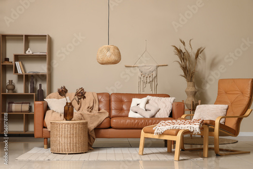 Comfortable sofa, armchair with footrest and dried flowers in vase on basket in interior of living room