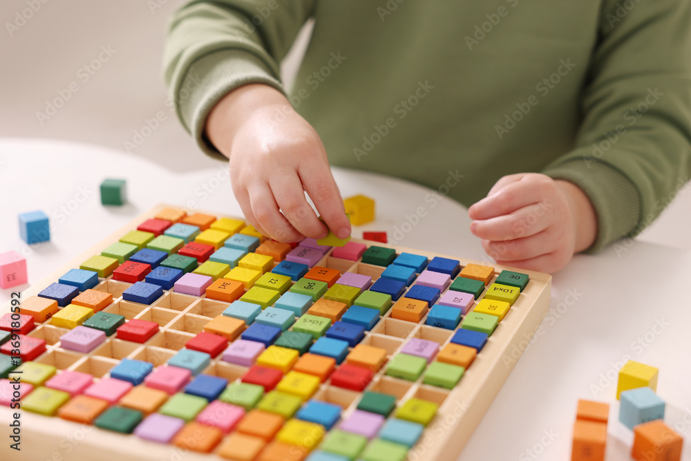 Fototapeta premium Motor skills development. Little boy playing with Times table tray indoors, closeup