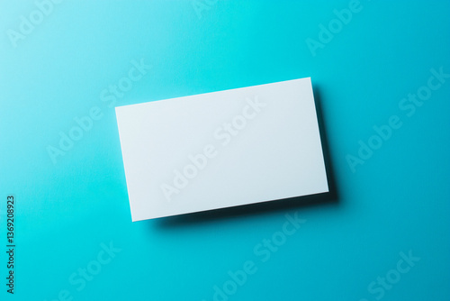 Obraz na płótnie Close-up of a blank white business card on a bright blue background, with soft shadows. w salonie