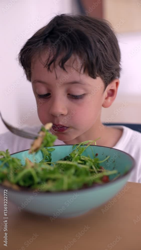Young boy eating salad from bowl, taking big bite with fork, healthy eating habits, casual moment of mindful childhood nutrition at home dining table Young boy eating salad from bowl, taking big bite with fork, healthy eating habits, casual moment of mindful childhood nutrition at home dining table