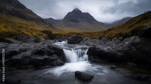 Panoramic view of waterfall at fairy pools on a grey autumn day. Water flowing over rocks with mountains in the background.