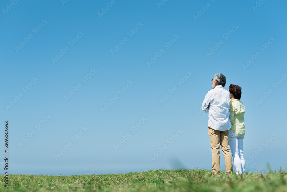 青空の下で海を眺めるシニア夫婦 青空の下で海を眺めるシニア夫婦