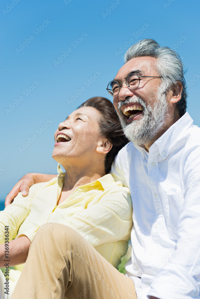 Fototapeta premium 青空の下で笑い合うシニア夫婦