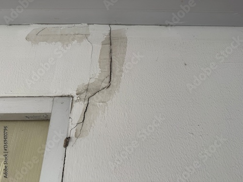 The cracks on the wall near the door frame indicate the impact of an earthquake. The wall has water stains around the cracks, suggesting damage that may have resulted from structural movement or stron