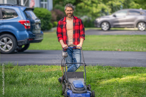 Man gardener cut the grass. Garden care. Electric lawn mower. Landscape design. Lawn mower landscaping. Backyard grass maintenance. Hispanic gardener. Lawnmower mow green grass. Summer job