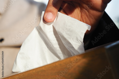 Slika na platnu Hand reaching for a tissue in a wooden box outdoors in bright daylight