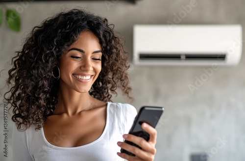 Smiling woman with remote control enjoys cool air from mini split conditioning system
