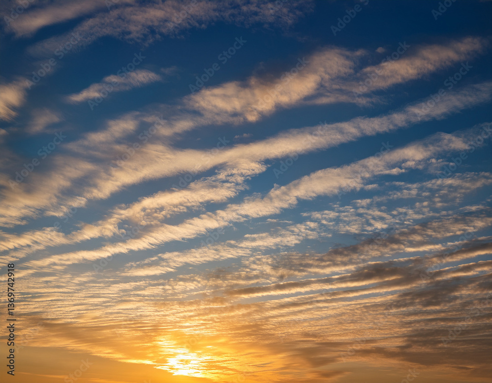 Fototapeta premium A morning sky brushed by golden sunlight shining through thin layers of high-altitude cirrostratus clouds.