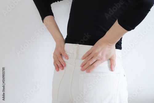 腰を押さえる女性、腰痛イメージ