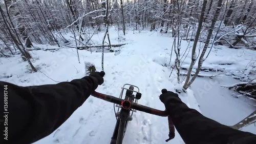 A man riding a bicycle through a winter forest