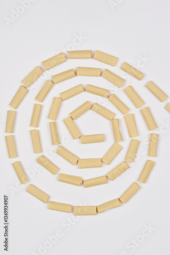 Small brown paper pieces are arranged in a spiral pattern on a white background