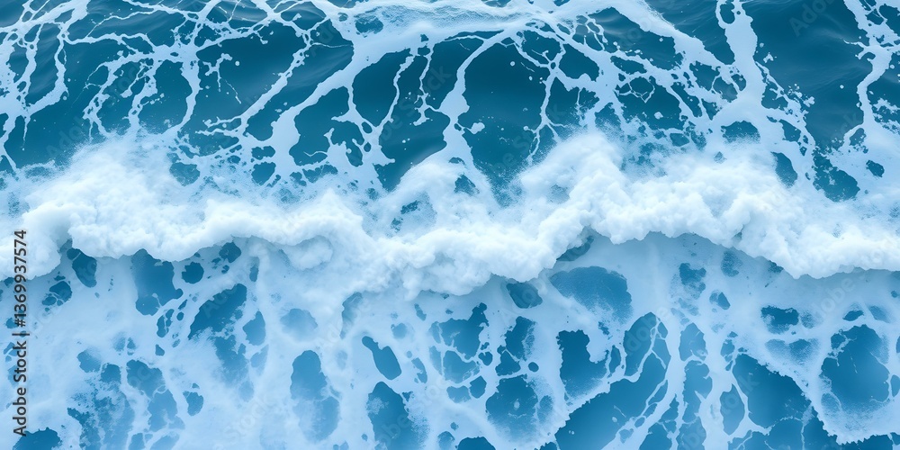 Naklejka premium Ocean's Rhythmic Embrace: An overhead, dynamic view of the ocean, showcasing the dance of waves and foam in a mesmerizing aquatic ballet. The rich, vivid blues contrast with the frothy whites.