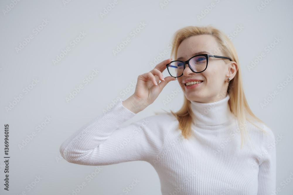 Young woman with glasses smiles while adjusting her eyewear in a bright indoor setting during daytime Young woman with glasses smiles while adjusting her eyewear in a bright indoor setting during daytime