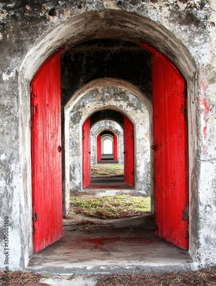 Fototapeta premium Vibrant Red Doors Framed by Arched Stone Walls in Historical Building