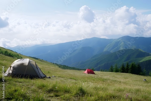 Tents pitched on a grassy mountain slope against a backdrop of mountains