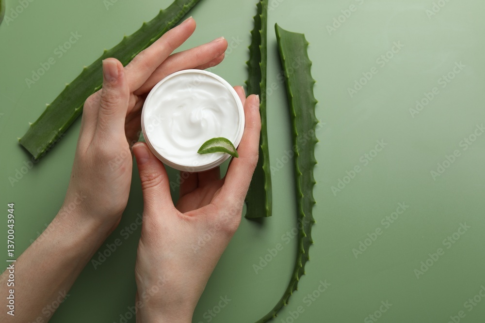 Fototapeta premium Woman with moisturizing cream and aloe vera leaves on green background, top view. Space for text