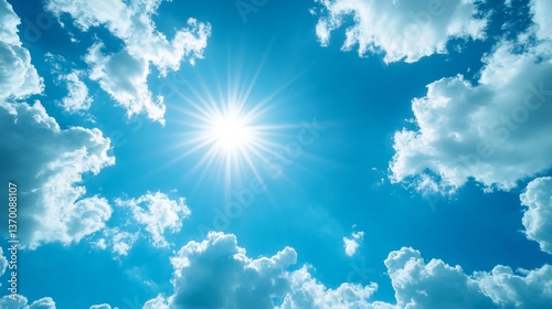 Clear blue sky filled with fluffy clouds and radiant sunlight over a serene landscape during midday