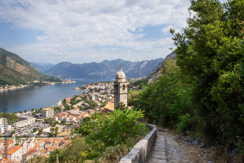 A picturesque coastal Budva town nestled in a mountainous bay, overlooked by a charming stone bell tower