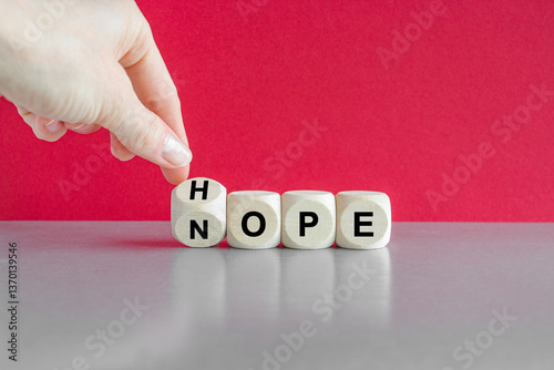Obraz na płótnie Hope or nope symbol. Hand turns a cube and changes the word 'nope' to 'hope'. Beautiful red background, gray table. Business and hope or nope concept. w salonie