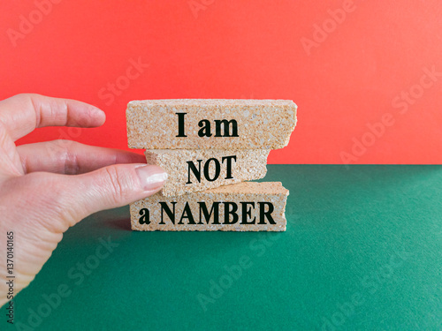 Obraz na płótnie The expression I am not a number written on beautiful brick blocks. Beautiful red background, green table. Businessman hand. Business your opinion matters concept. w salonie