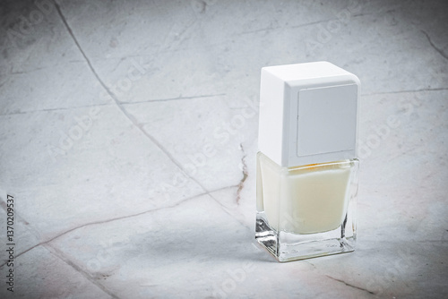 A sleek bottle of white nail polish rests on a marble surface